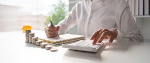 Young woman sitting at a table with a calculator and notepad